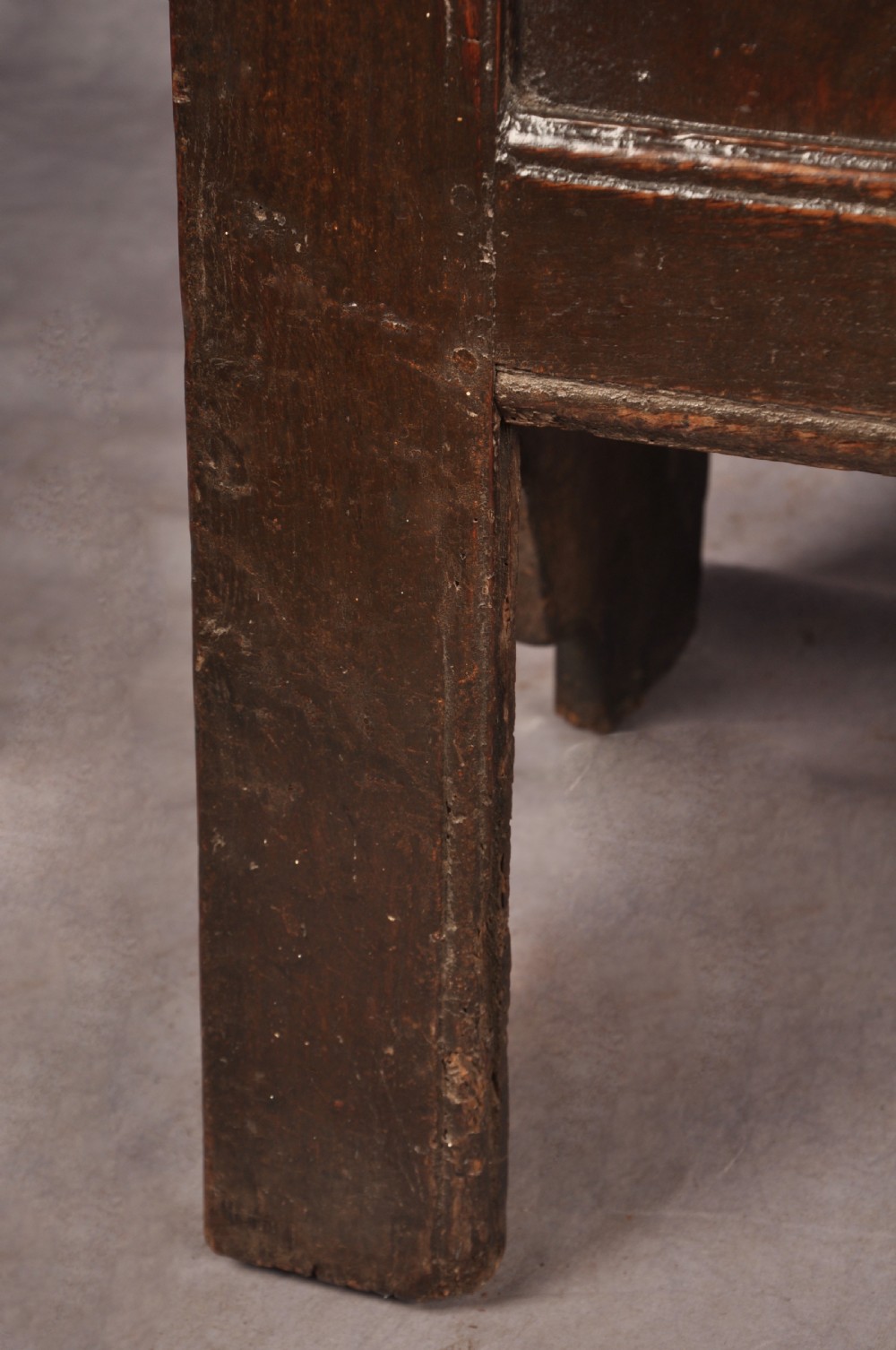 A dark oak 17th century coffer featuring carved lozenge motifs across three front panels beneath an arcaded frieze and iron lockplate. View VI