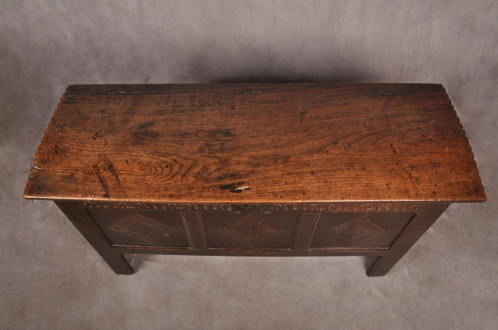 A dark oak 17th century coffer featuring carved lozenge motifs across three front panels beneath an arcaded frieze and iron lockplate. View VII