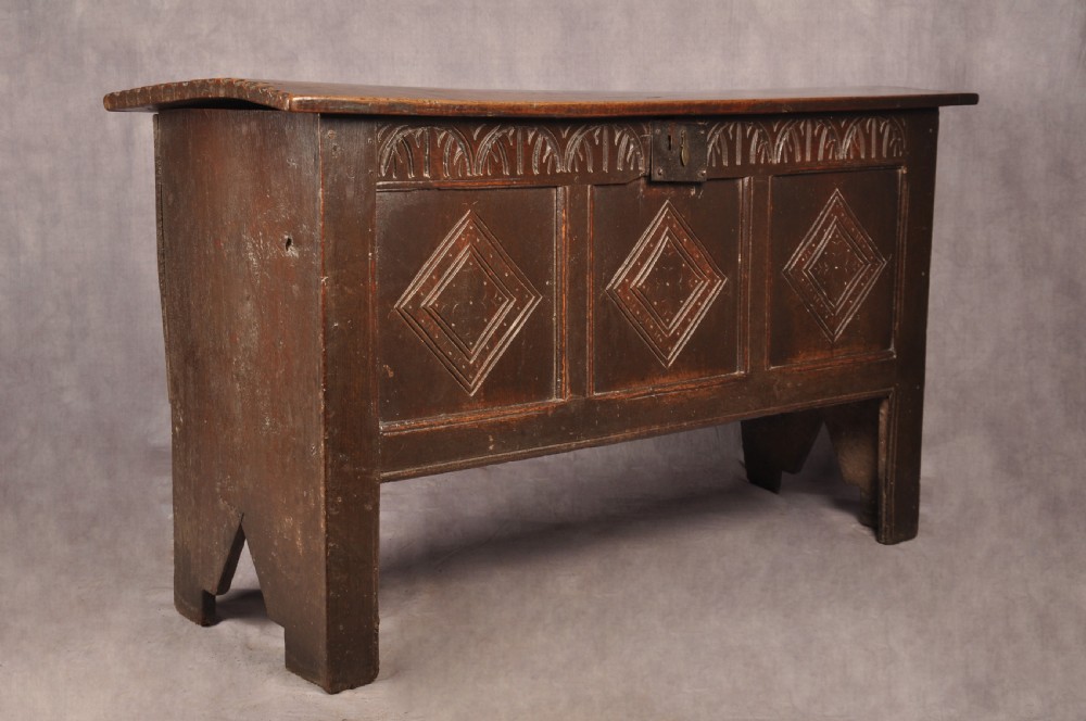A dark oak 17th century coffer featuring carved lozenge motifs across three front panels beneath an arcaded frieze and iron lockplate. View VIII