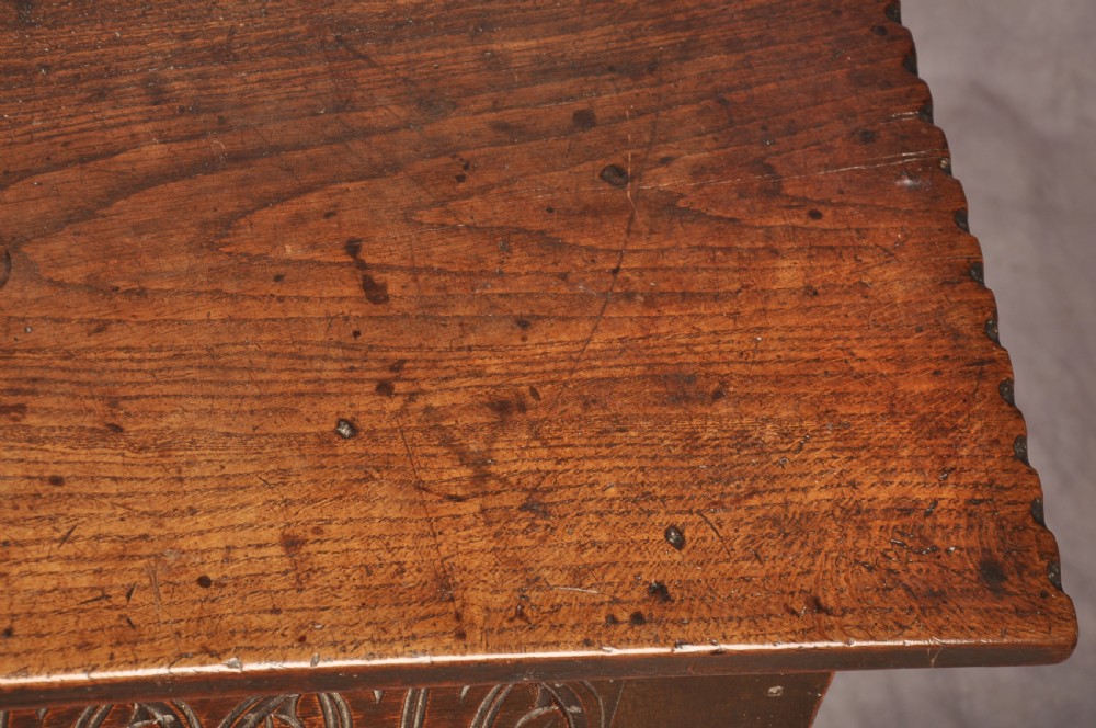 A dark oak 17th century coffer featuring carved lozenge motifs across three front panels beneath an arcaded frieze and iron lockplate. View IX
