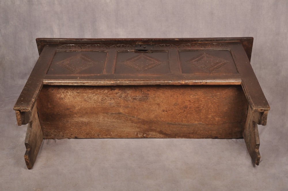 A dark oak 17th century coffer featuring carved lozenge motifs across three front panels beneath an arcaded frieze and iron lockplate. View XI