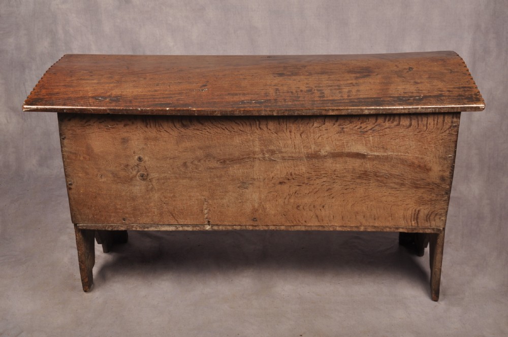 A dark oak 17th century coffer featuring carved lozenge motifs across three front panels beneath an arcaded frieze and iron lockplate. View XII