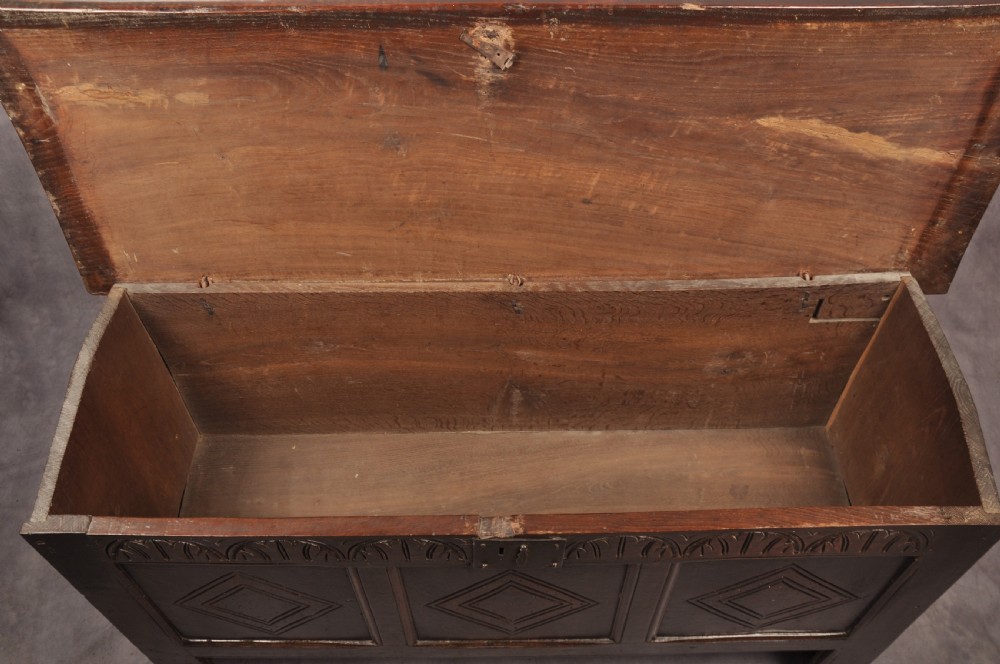 A dark oak 17th century coffer featuring carved lozenge motifs across three front panels beneath an arcaded frieze and iron lockplate. View XIII