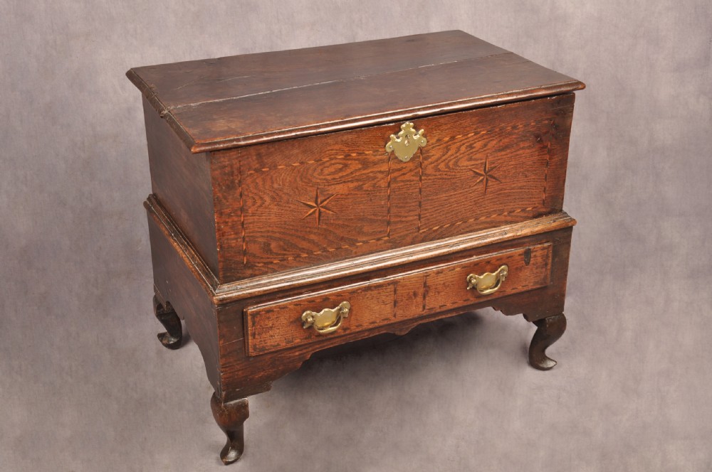 An early eighteenth-century oak coffer bach with star inlay details, a hinged top lid, a single lower drawer, and brass handles. View II