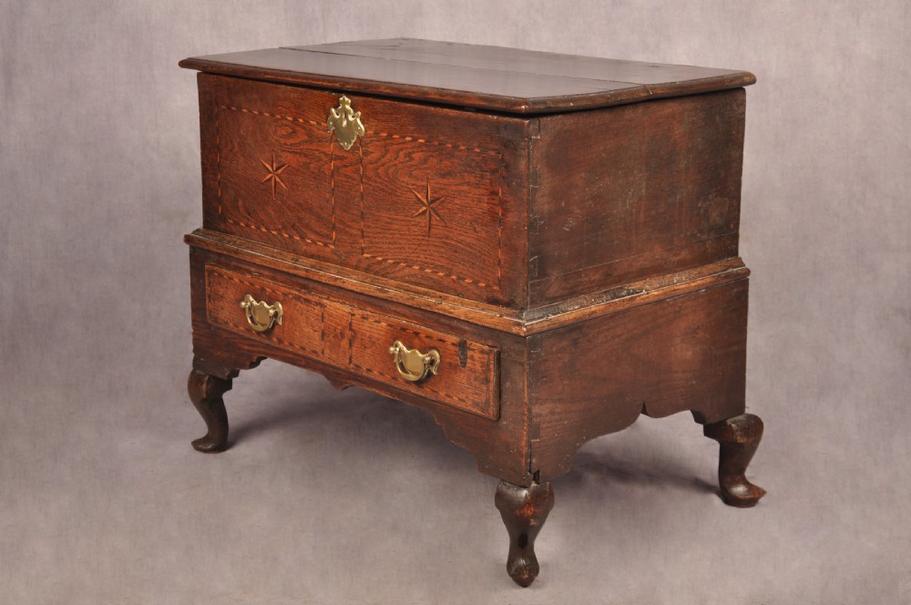 An early eighteenth-century oak coffer bach with star inlay details, a hinged top lid, a single lower drawer, and brass handles. View III