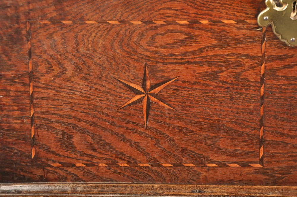 An early eighteenth-century oak coffer bach with star inlay details, a hinged top lid, a single lower drawer, and brass handles. View V