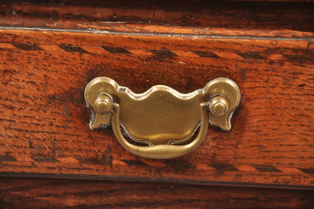 An early eighteenth-century oak coffer bach with star inlay details, a hinged top lid, a single lower drawer, and brass handles. View VII