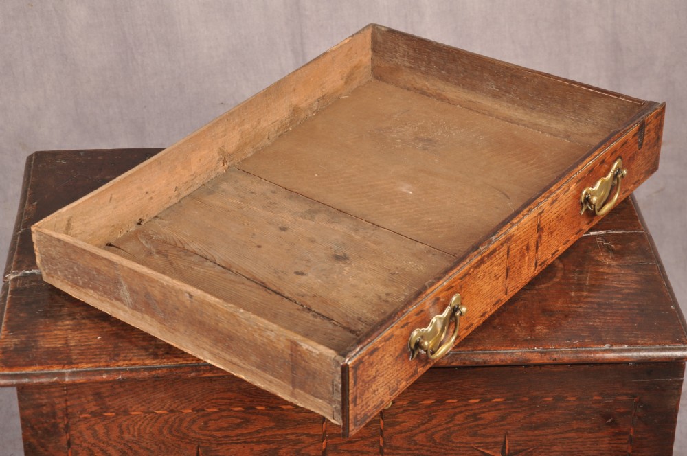 An early eighteenth-century oak coffer bach with star inlay details, a hinged top lid, a single lower drawer, and brass handles. View IX