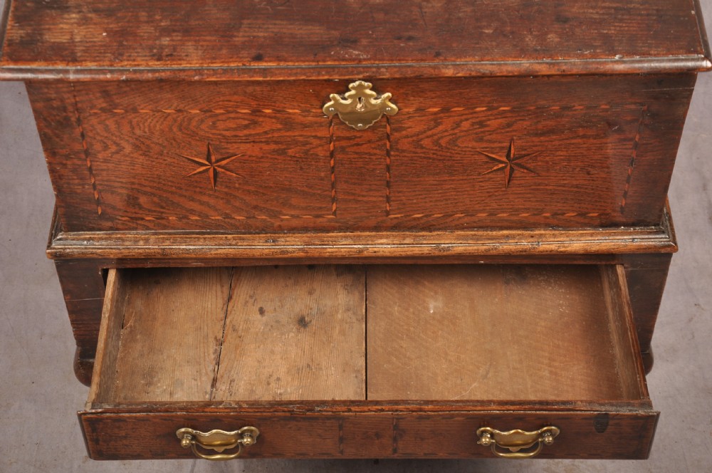 An early eighteenth-century oak coffer bach with star inlay details, a hinged top lid, a single lower drawer, and brass handles. View XII