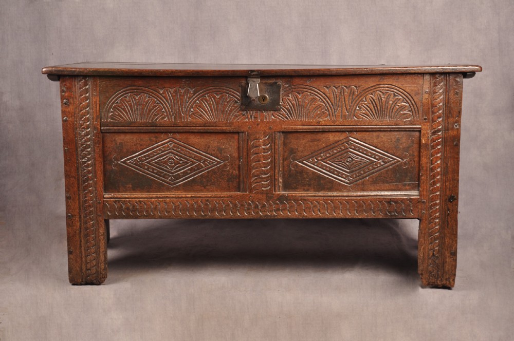 A small 17th-century dark oak coffer featuring carved lozenge and lunette patterns across the front with an iron escutcheon plate. View II