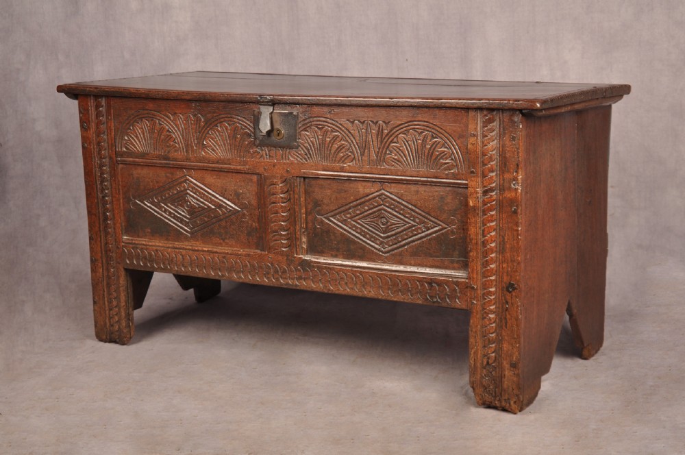 A small 17th-century dark oak coffer featuring carved lozenge and lunette patterns across the front with an iron escutcheon plate. View III