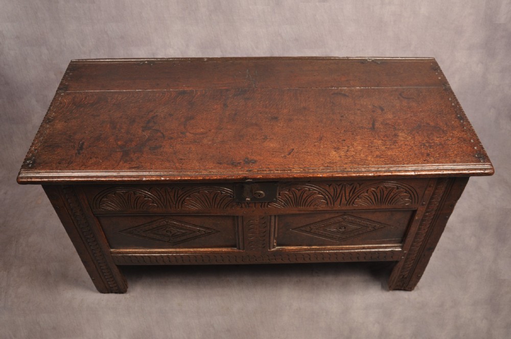 A small 17th-century dark oak coffer featuring carved lozenge and lunette patterns across the front with an iron escutcheon plate. View IV