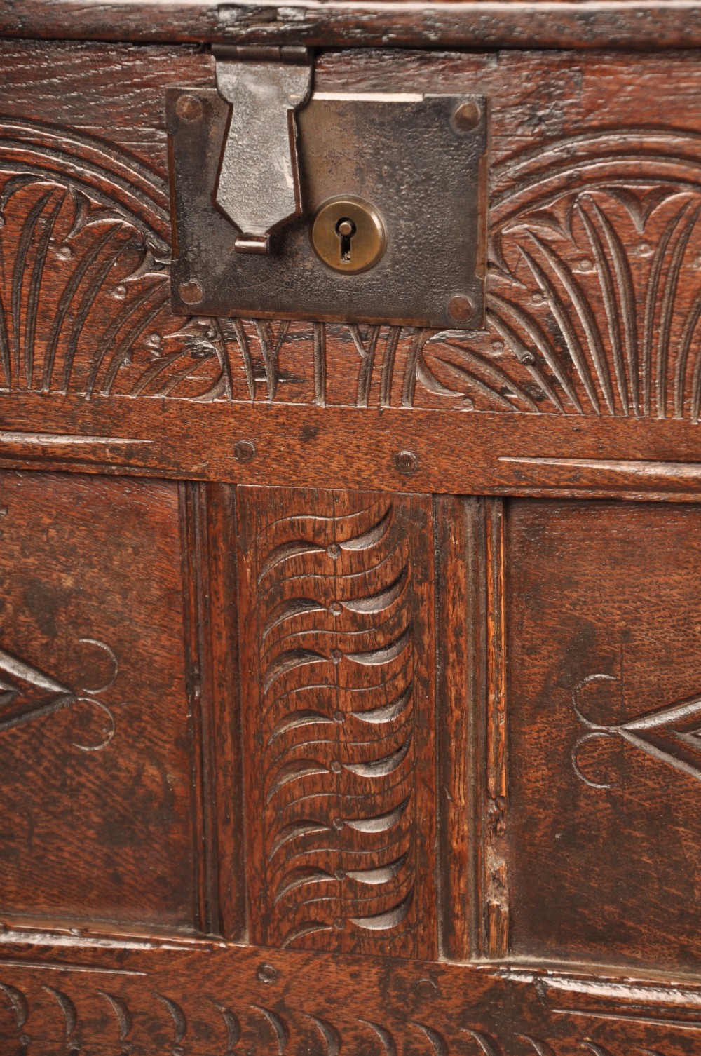 A small 17th-century dark oak coffer featuring carved lozenge and lunette patterns across the front with an iron escutcheon plate. View VI