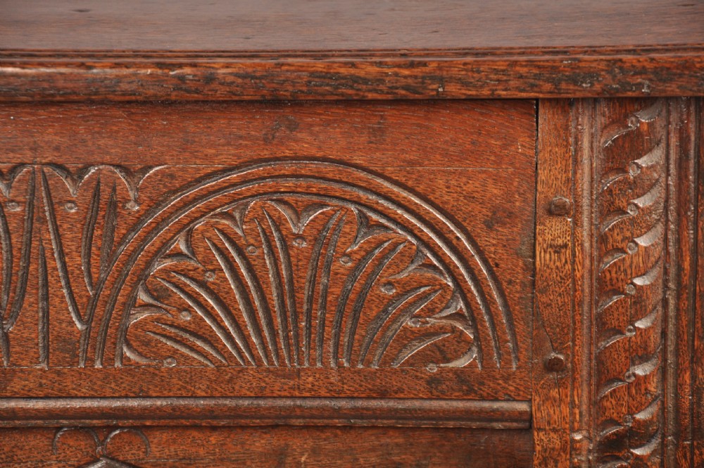 A small 17th-century dark oak coffer featuring carved lozenge and lunette patterns across the front with an iron escutcheon plate. View VII