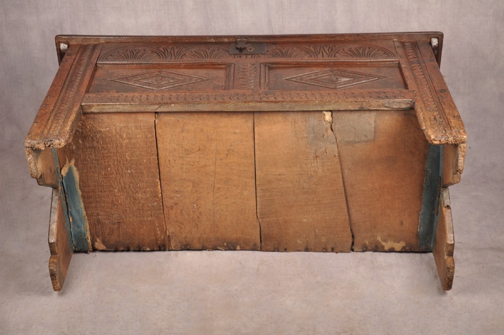 A small 17th-century dark oak coffer featuring carved lozenge and lunette patterns across the front with an iron escutcheon plate. View XII