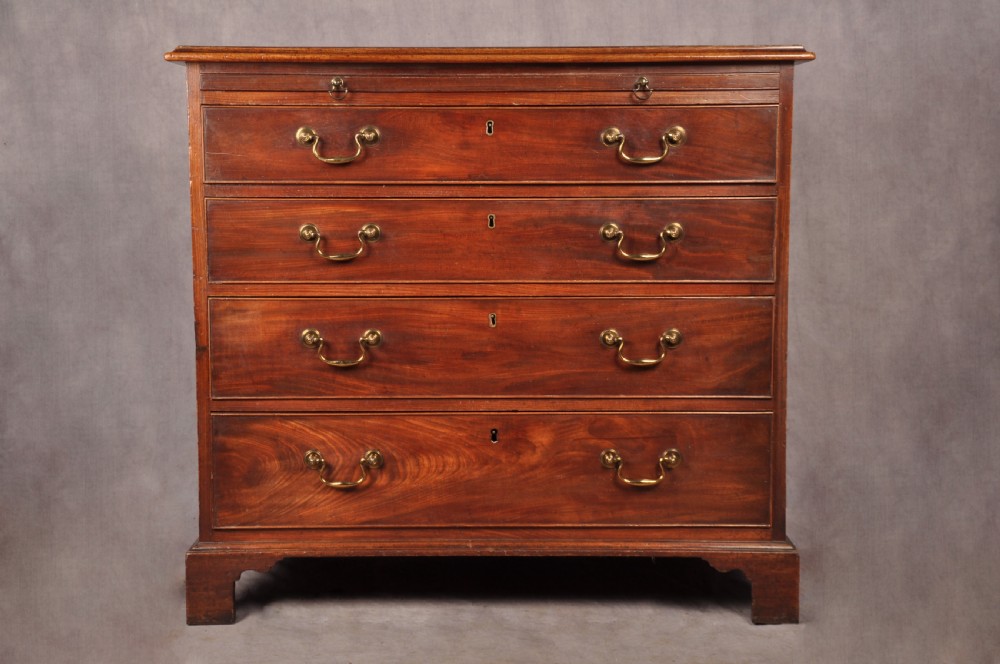 An 18th-century Georgian mahogany chest of drawers featuring four graduated drawers with brass swan-neck handles, keyholes, a pull-out brushing slide, and bracket feet.