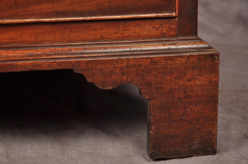 An 18th-century Georgian mahogany chest of drawers featuring four graduated drawers with brass swan-neck handles, keyholes, a pull-out brushing slide, and bracket feet. View V