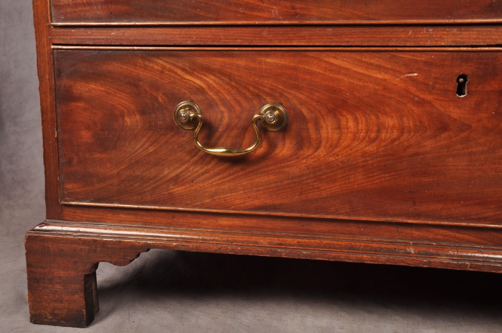 An 18th-century Georgian mahogany chest of drawers featuring four graduated drawers with brass swan-neck handles, keyholes, a pull-out brushing slide, and bracket feet. View VI
