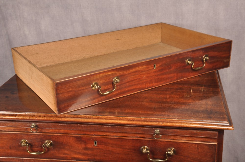 An 18th-century Georgian mahogany chest of drawers featuring four graduated drawers with brass swan-neck handles, keyholes, a pull-out brushing slide, and bracket feet. View IX