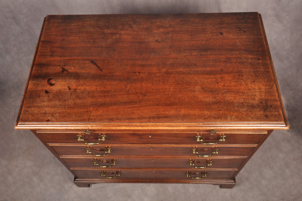 An 18th-century Georgian mahogany chest of drawers featuring four graduated drawers with brass swan-neck handles, keyholes, a pull-out brushing slide, and bracket feet. View XI