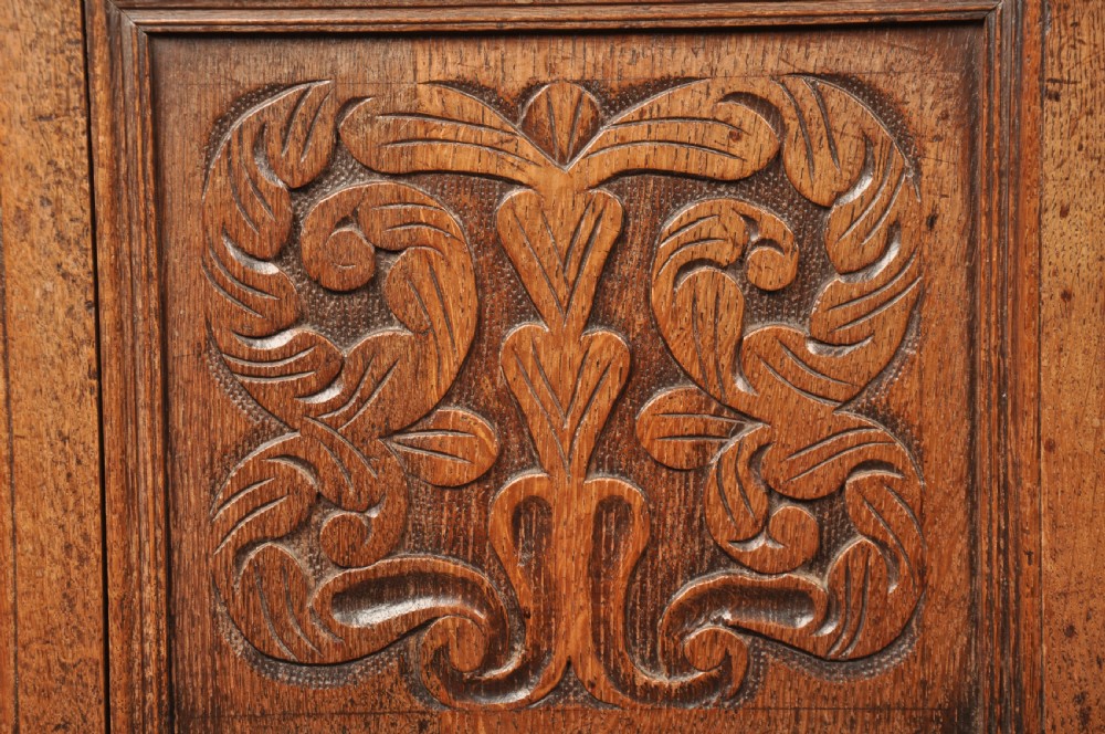 An 18th-century carved oak mule chest featuring three relief-carved front panels, a carved dated top frieze reading 1712, and two lower geometric drawers. View VIII