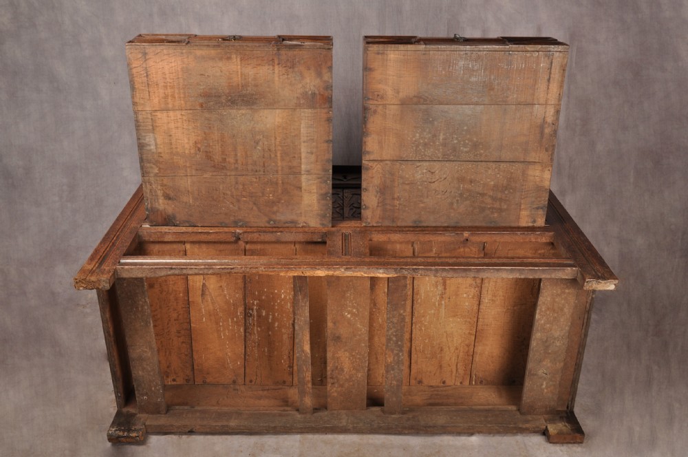 An 18th-century carved oak mule chest featuring three relief-carved front panels, a carved dated top frieze reading 1712, and two lower geometric drawers. View XV