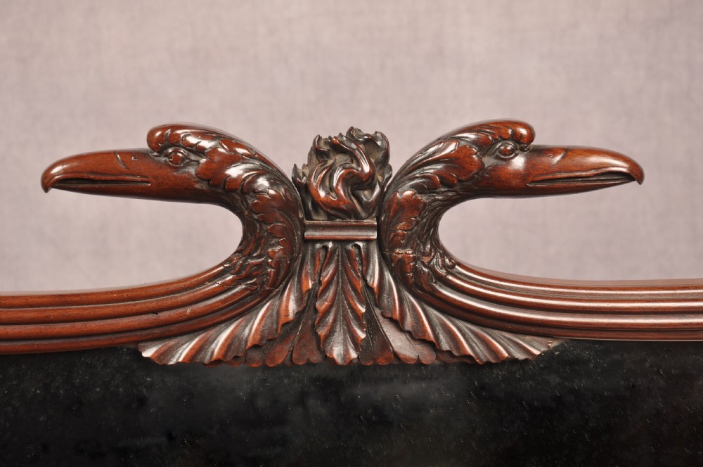 An antique Regency mahogany sideboard featuring flame mahogany panel doors, brass lion mask ring handles, spiral turned columns, hairy paw feet, and a central backboard mirror. View VI