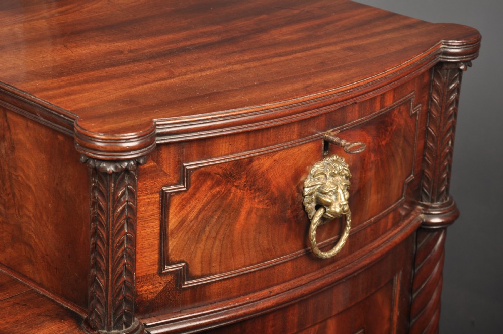 An antique Regency mahogany sideboard featuring flame mahogany panel doors, brass lion mask ring handles, spiral turned columns, hairy paw feet, and a central backboard mirror. View XI