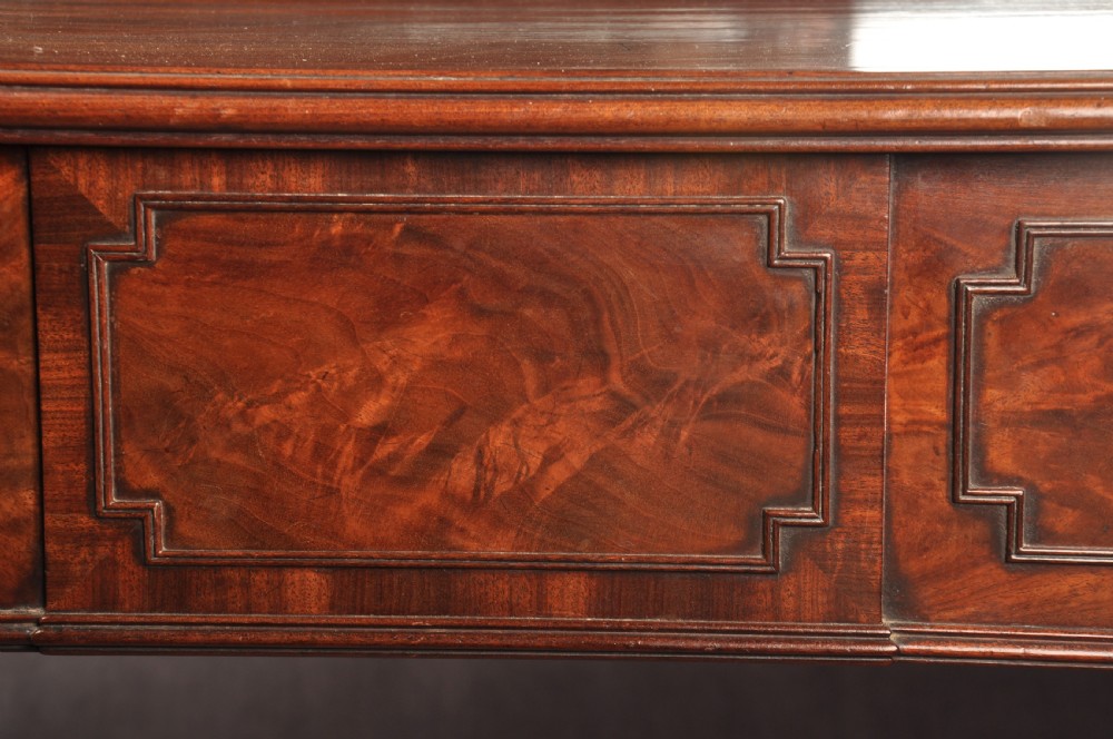 An antique Regency mahogany sideboard featuring flame mahogany panel doors, brass lion mask ring handles, spiral turned columns, hairy paw feet, and a central backboard mirror. View XV