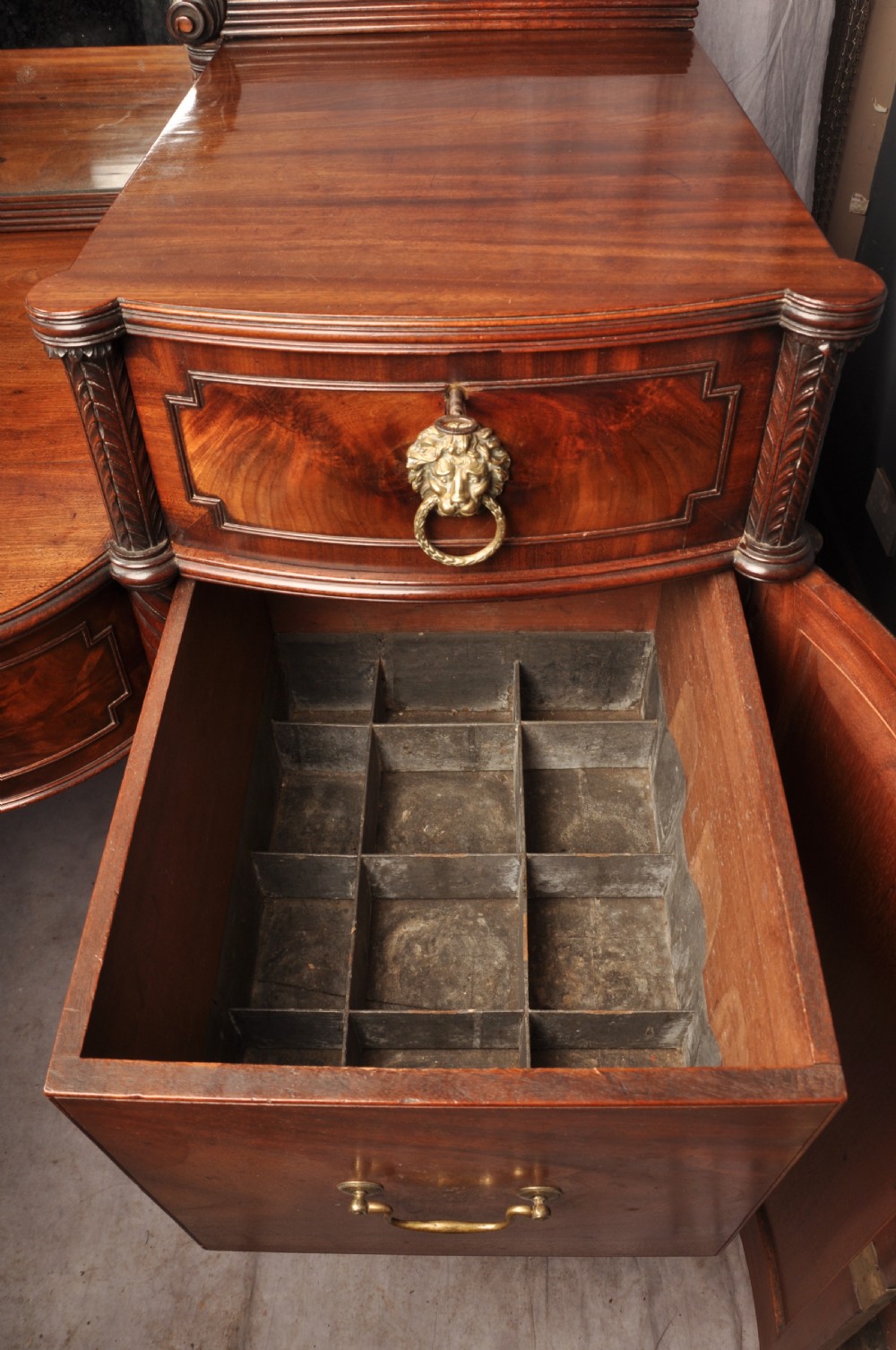 An antique Regency mahogany sideboard featuring flame mahogany panel doors, brass lion mask ring handles, spiral turned columns, hairy paw feet, and a central backboard mirror. View XVIII