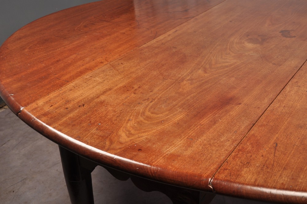 An 18th-century mahogany drop-leaf gateleg table with tapered legs, pad feet, and a scalloped apron on a plain background. View VIII