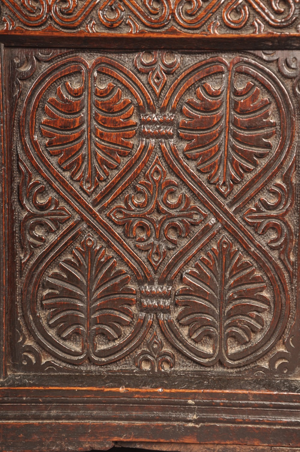 A dark 17th-century oak coffer with three relief-carved front panels and a top frieze inscribed with the initials TH and date 1665. View II