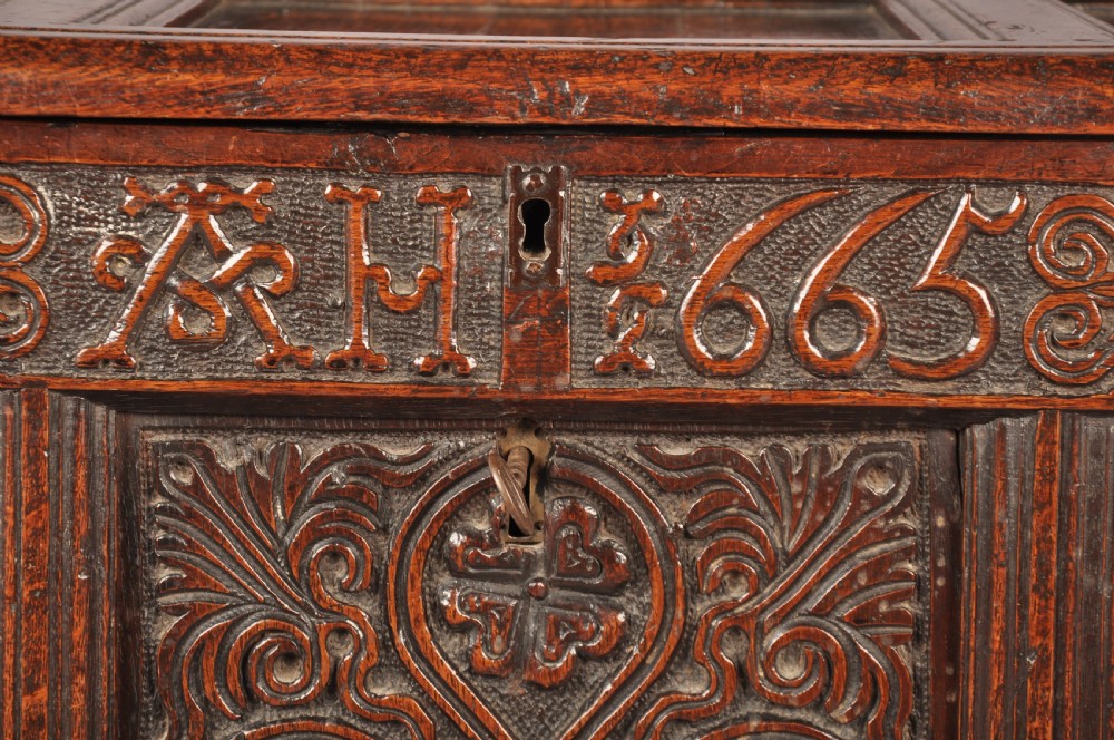 A dark 17th-century oak coffer with three relief-carved front panels and a top frieze inscribed with the initials TH and date 1665. View III