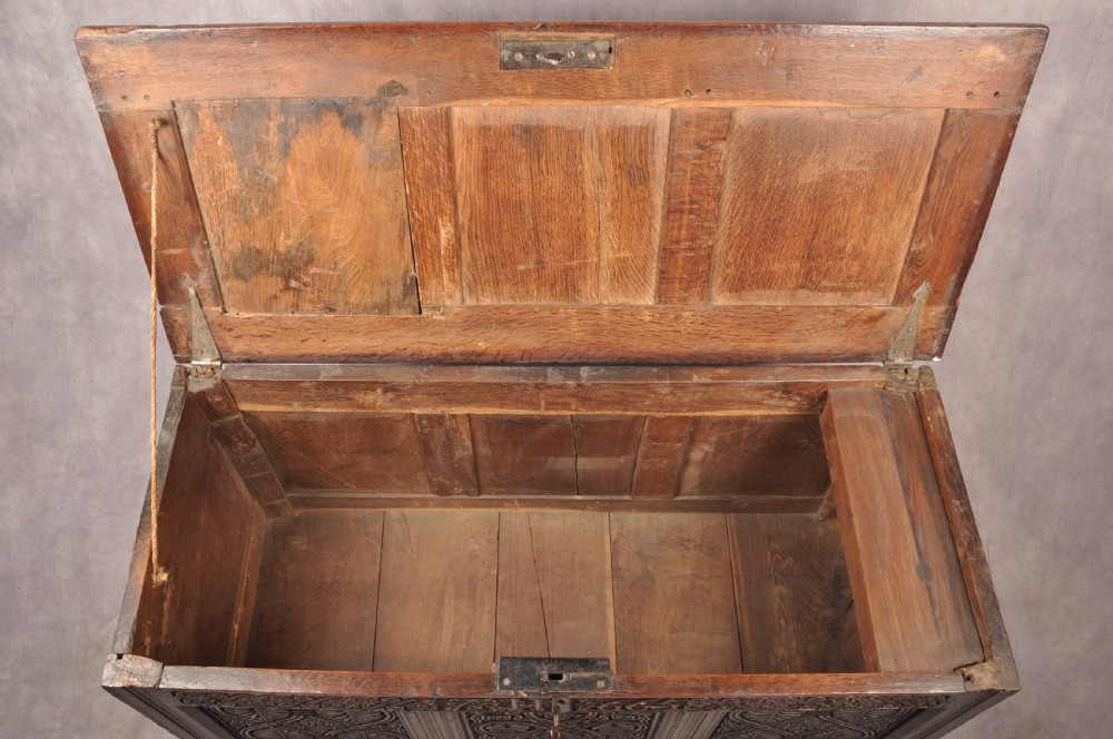 A dark 17th-century oak coffer with three relief-carved front panels and a top frieze inscribed with the initials TH and date 1665. View VIII