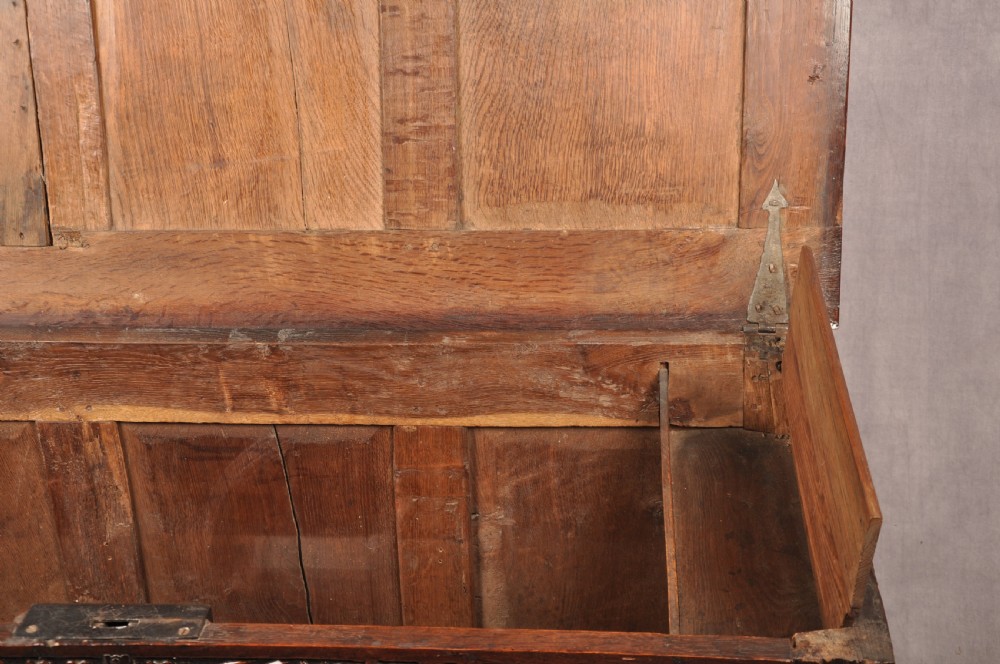 A dark 17th-century oak coffer with three relief-carved front panels and a top frieze inscribed with the initials TH and date 1665. View IX