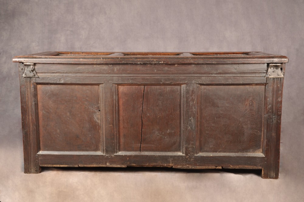 A dark 17th-century oak coffer with three relief-carved front panels and a top frieze inscribed with the initials TH and date 1665. View XI