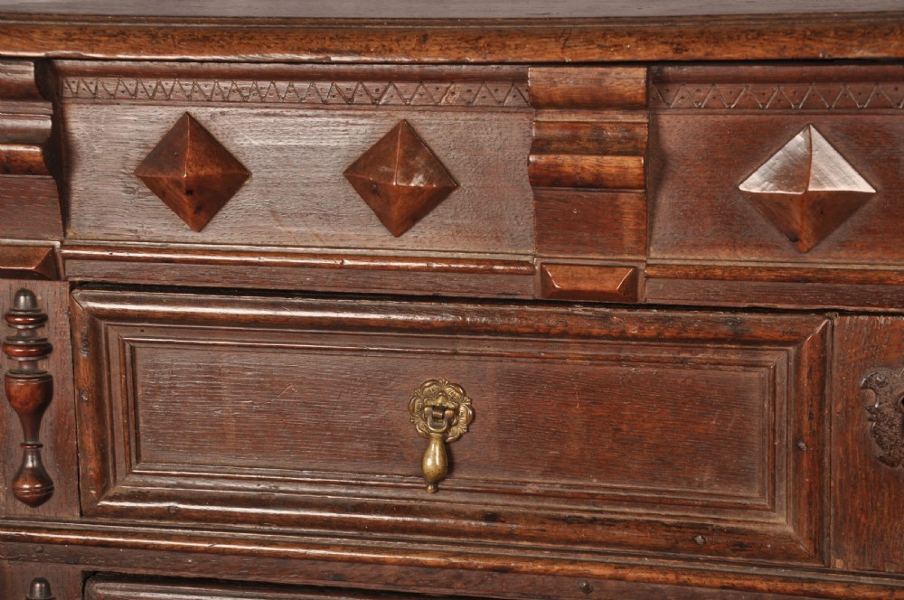 A 17th-century dark oak chest of drawers featuring geometric mouldings, split baluster details, brass drop handles, and a scalloped apron. View III