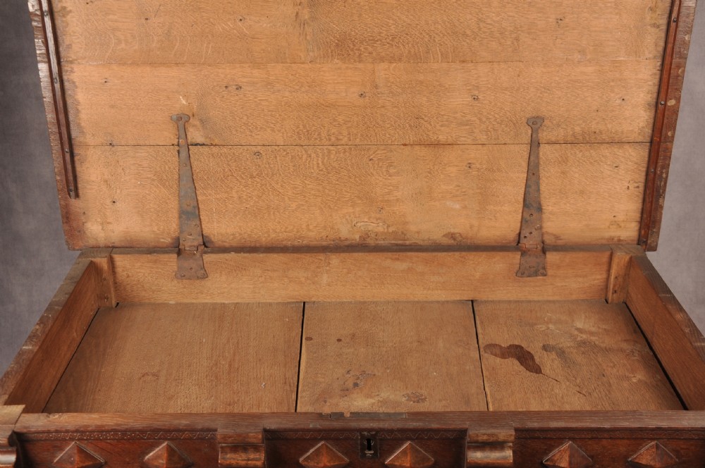 A 17th-century dark oak chest of drawers featuring geometric mouldings, split baluster details, brass drop handles, and a scalloped apron. View XVI