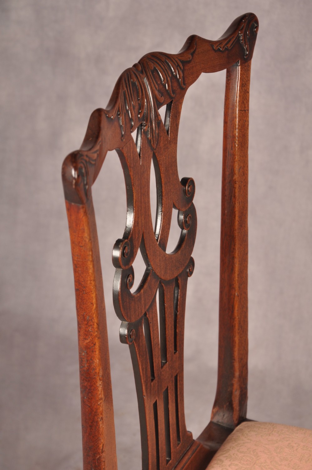 A pair of 18th-century mahogany Chippendale side chairs featuring carved pierced back splats and light patterned upholstered seat pads. View V