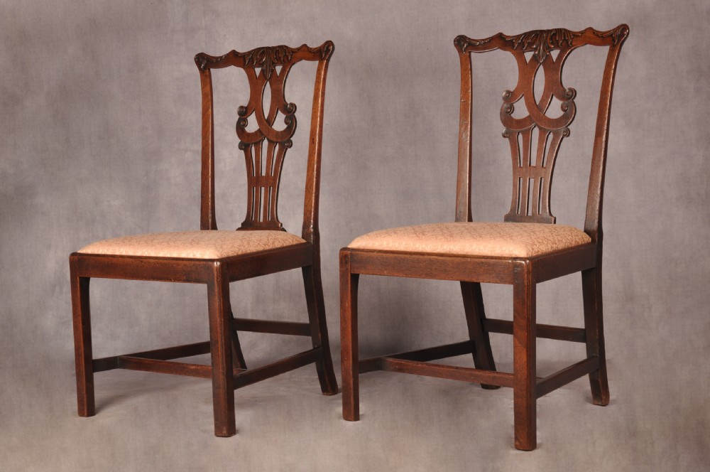 A pair of 18th-century mahogany Chippendale side chairs featuring carved pierced back splats and light patterned upholstered seat pads. View VIII