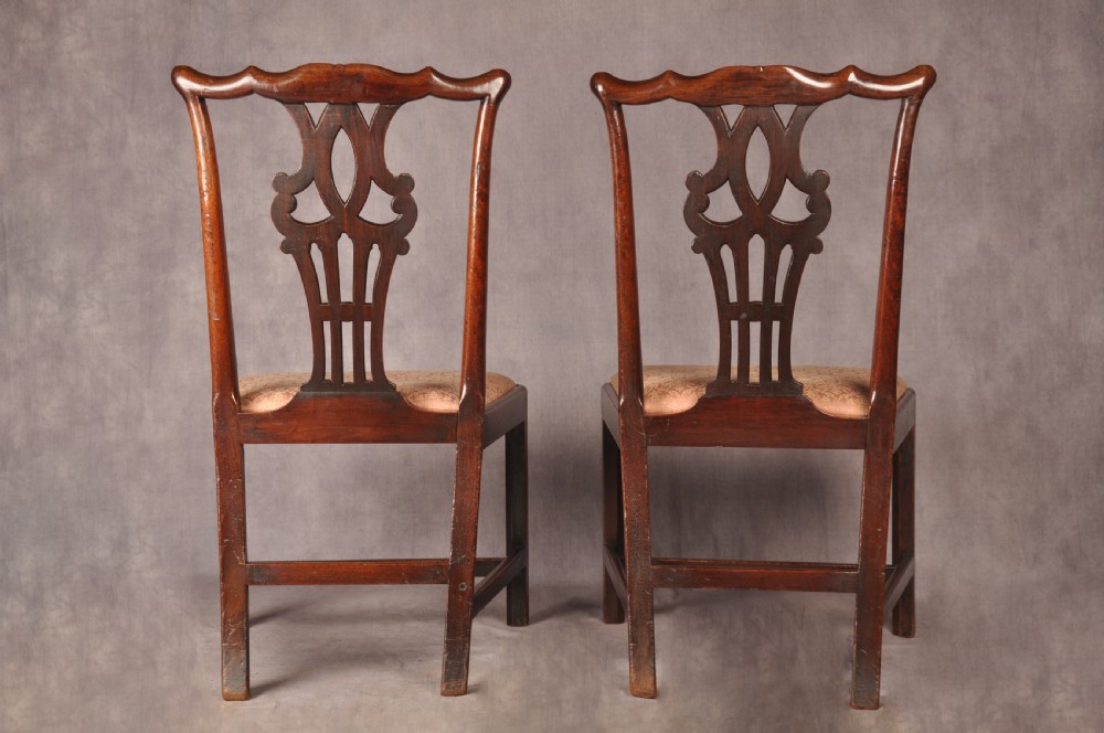 A pair of 18th-century mahogany Chippendale side chairs featuring carved pierced back splats and light patterned upholstered seat pads. View X
