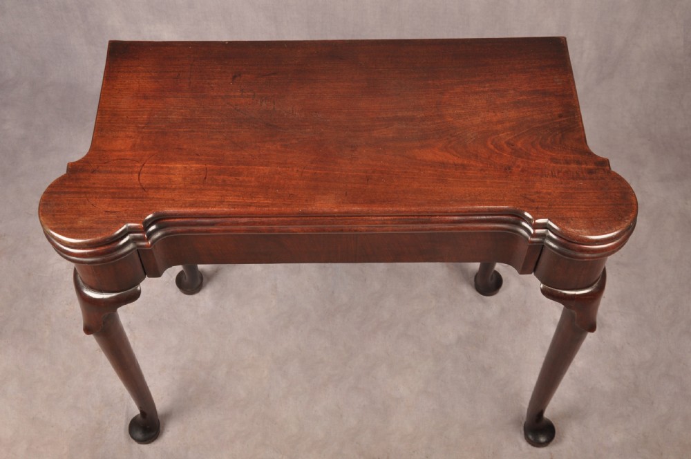 An 18th-century dark mahogany triple-top card table with shaped cabriole legs ending in pad feet. View II