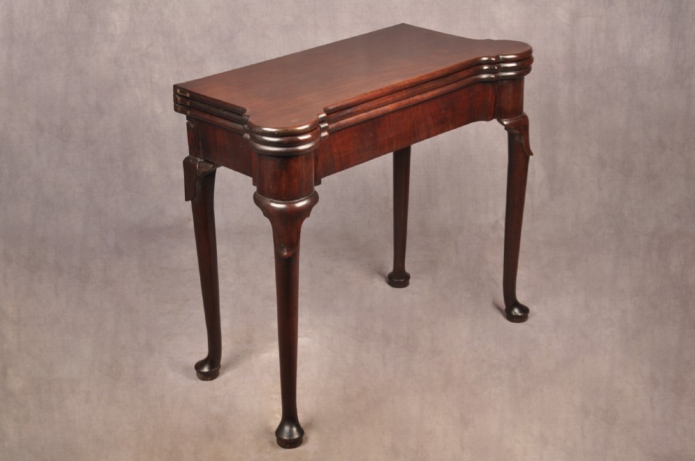 An 18th-century dark mahogany triple-top card table with shaped cabriole legs ending in pad feet. View III
