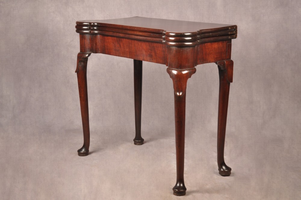 An 18th-century dark mahogany triple-top card table with shaped cabriole legs ending in pad feet. View IV
