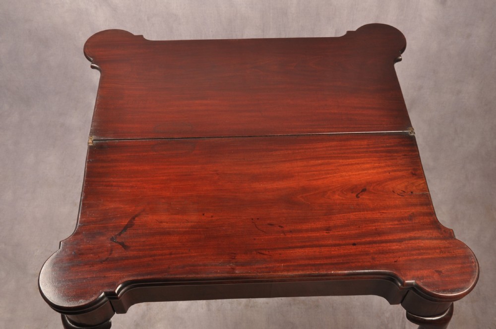 An 18th-century dark mahogany triple-top card table with shaped cabriole legs ending in pad feet. View VII