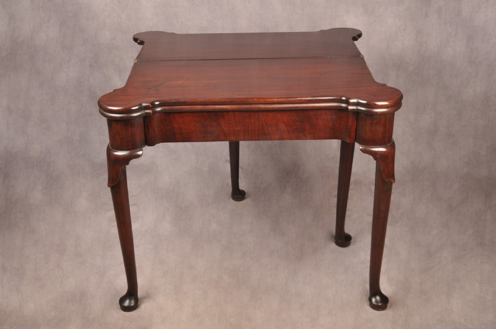 An 18th-century dark mahogany triple-top card table with shaped cabriole legs ending in pad feet. View X