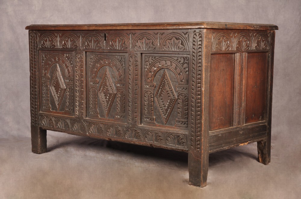 A 17th-century dark oak coffer featuring three carved arcaded panels with central diamond lozenge designs and carved lunette friezes. View III