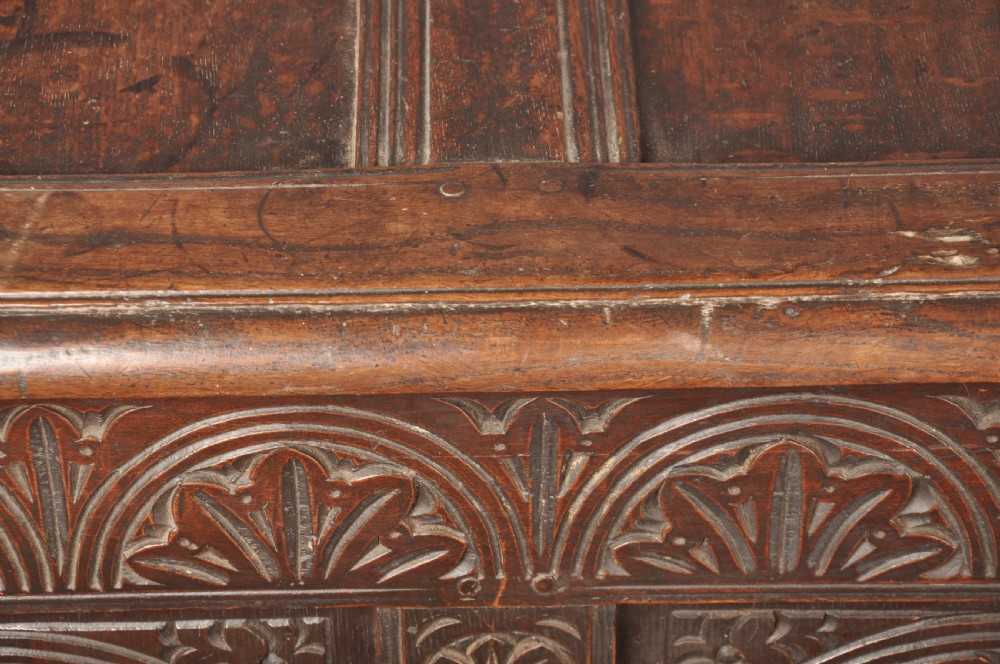 A 17th-century dark oak coffer featuring three carved arcaded panels with central diamond lozenge designs and carved lunette friezes. View V