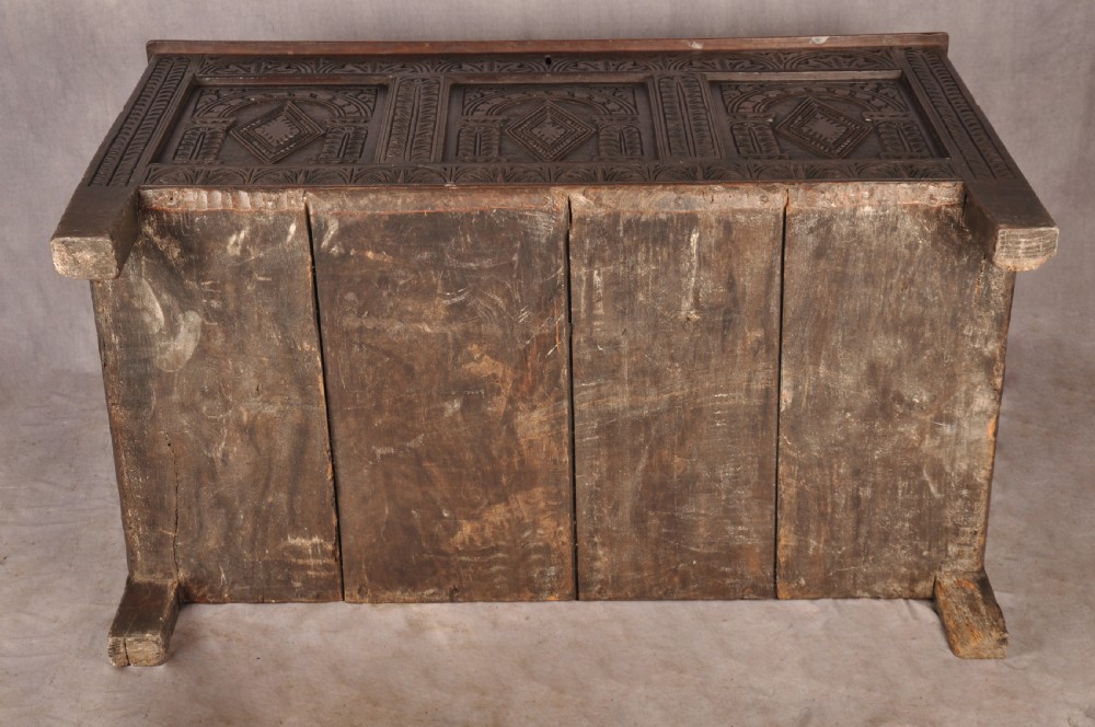 A 17th-century dark oak coffer featuring three carved arcaded panels with central diamond lozenge designs and carved lunette friezes. View XI