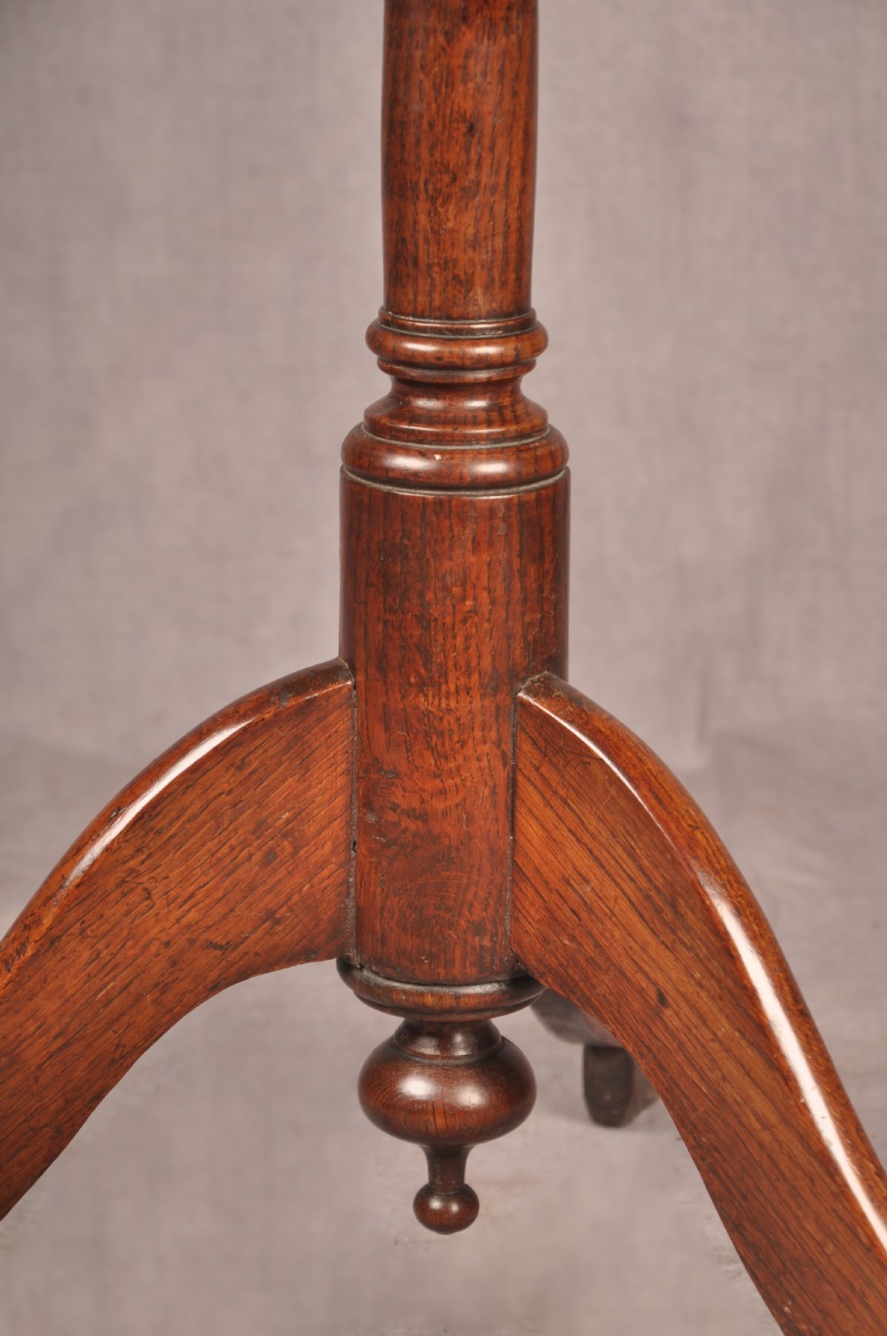 An 18th-century dark oak tripod table featuring a circular top, turned spindle birdcage stem, and three splayed cabriole legs. View IV